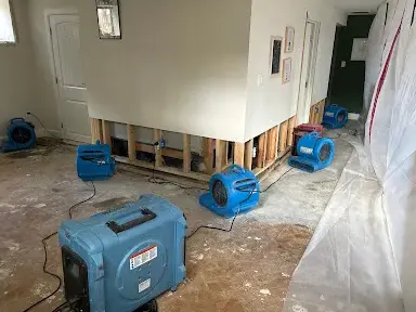 Containment plastic and air movers drying a room with the lower drywall cut out