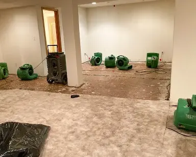 Air movers and a dehumidifier set across a basement after the carpet came up