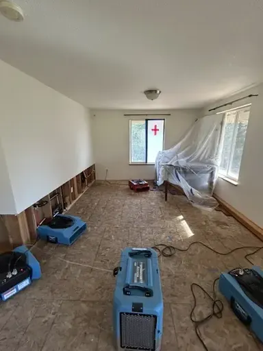 Air movers drying a subfloor under a window after a water loss